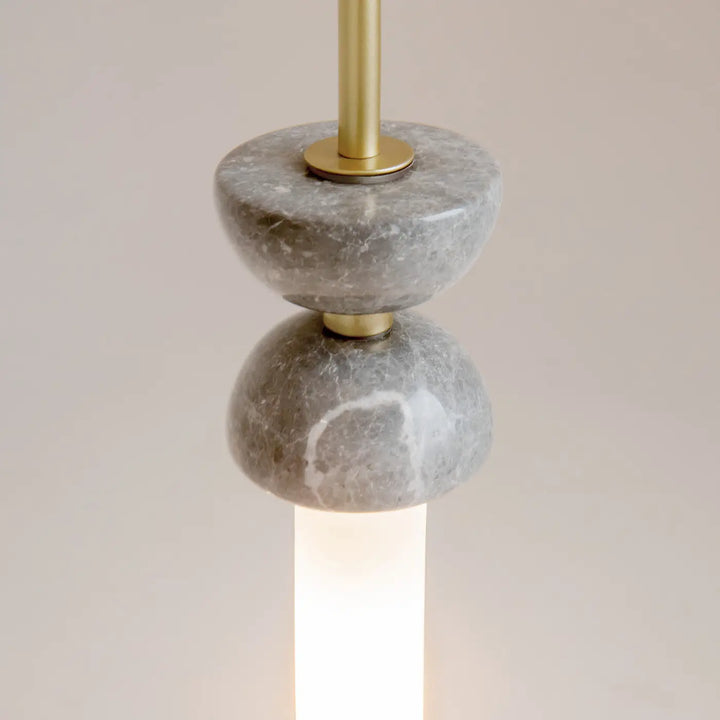 Suspension kyoto cylindre en marbre gris avec accents laiton et lumière douce sur base cylindrique en acier noir