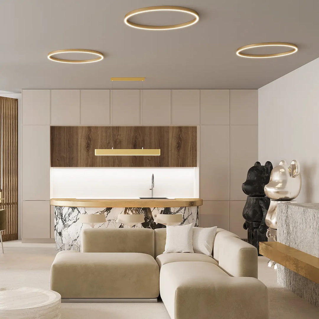 Modern minimalist living room with beige sectional sofa, marble island, and circular led suspension rim trois anneaux luminaire