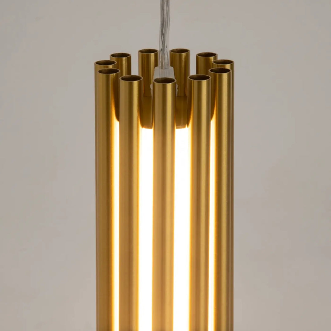 Suspension luminaire sonata cylindre en acier doré avec tubes verticaux et suspension led intégrée au-dessus d’un îlot