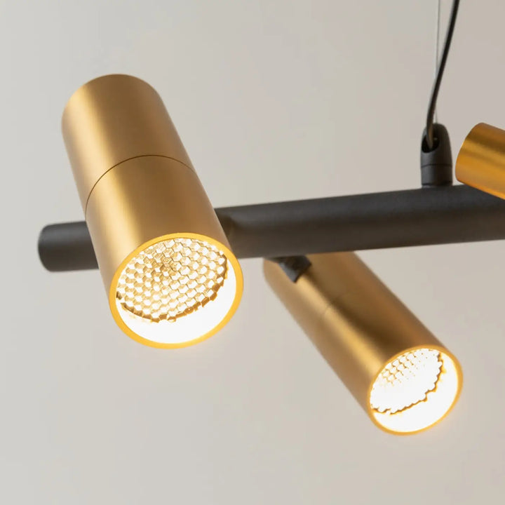 Suspension led tau ruban noué en acier noir avec spots cylindriques dorés au-dessus d’une barre horizontale noire