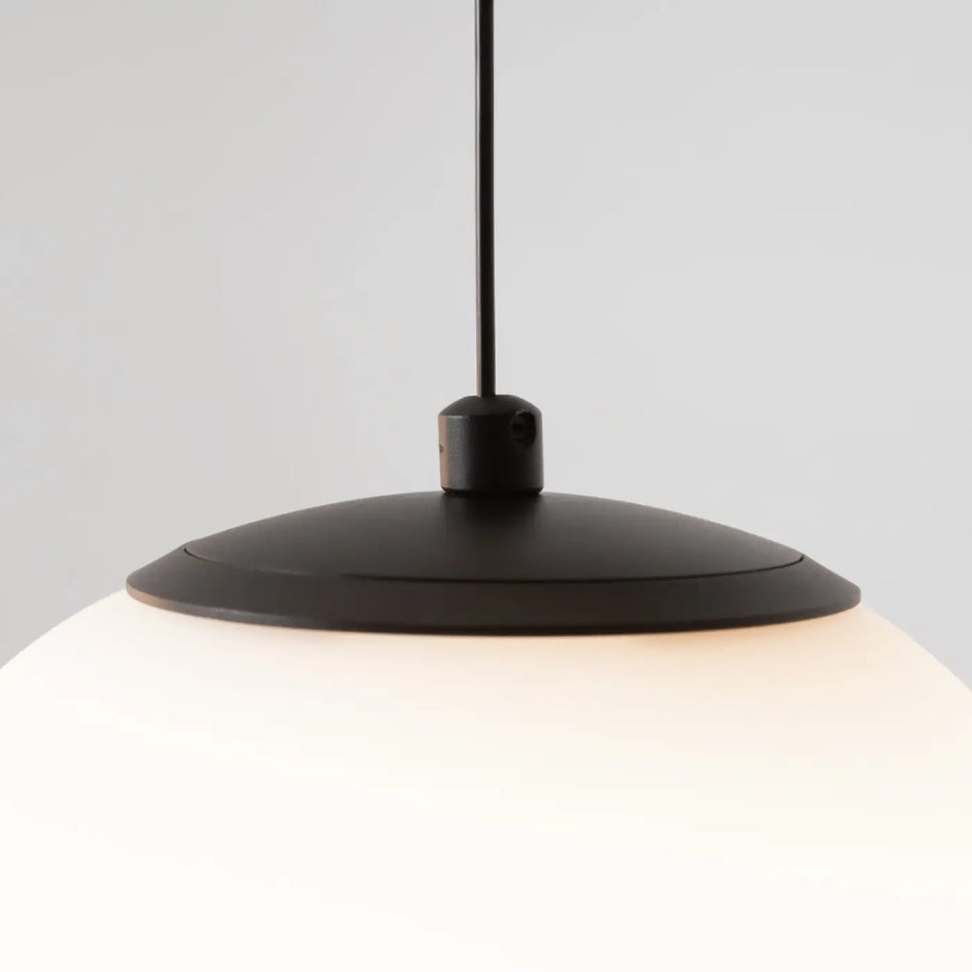 Suspension luminaire twins avec trois globes led en verre dépoli au-dessus d’une table finition mate noire