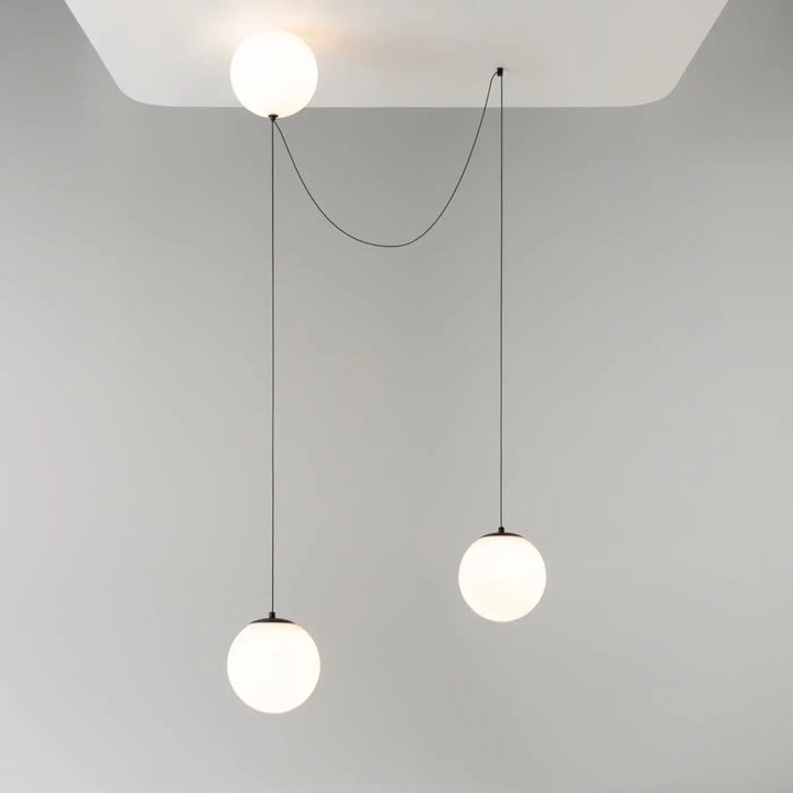 Suspension luminaire twins avec trois globes en verre dépoli blanc suspendus par cordons noirs au-dessus d’une table led