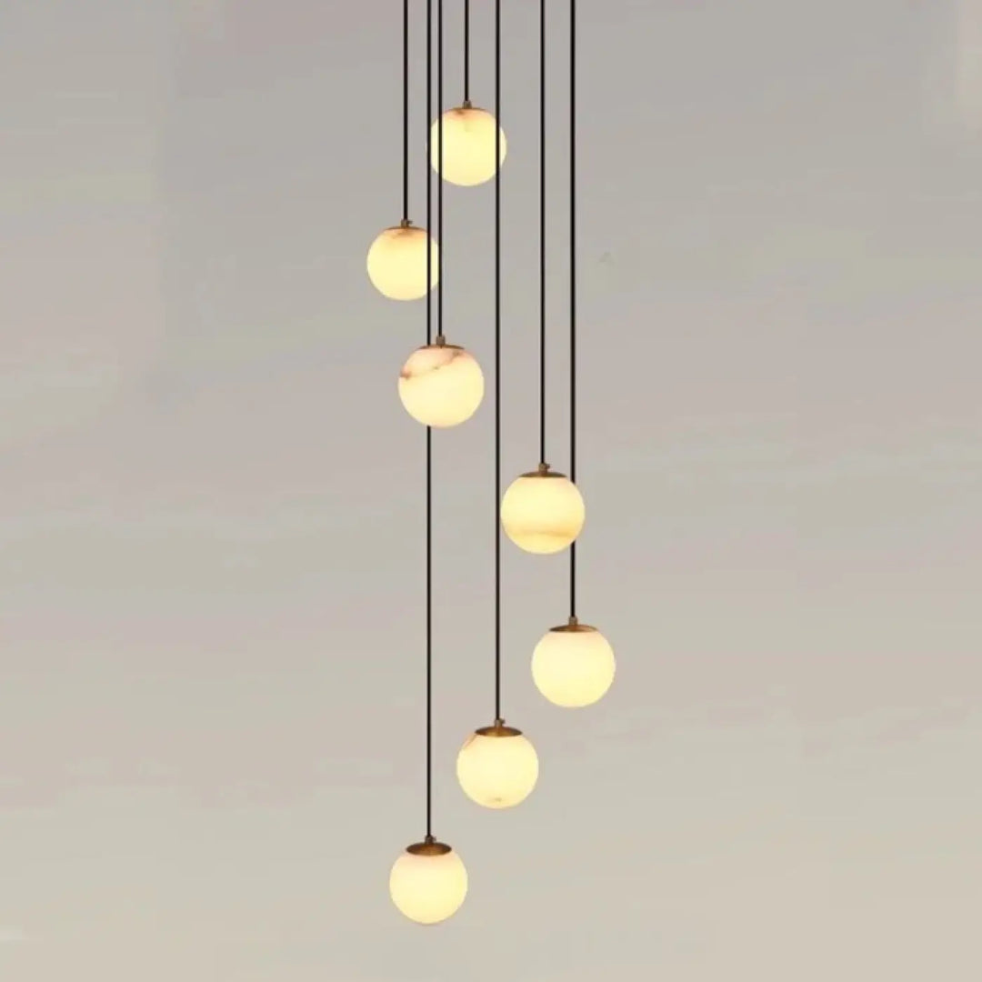 Suspension luminaire souble avec sept boules en verre marbré chic suspendues par cordons noirs pour univers art déco