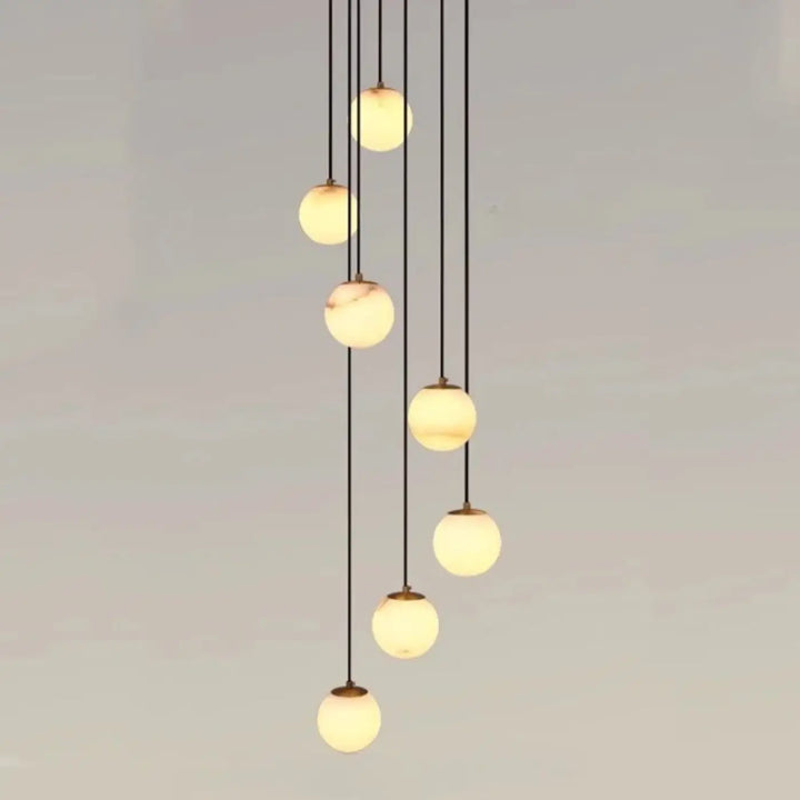 Suspension luminaire souble avec sept boules en verre marbré chic suspendues par cordons noirs pour univers art déco