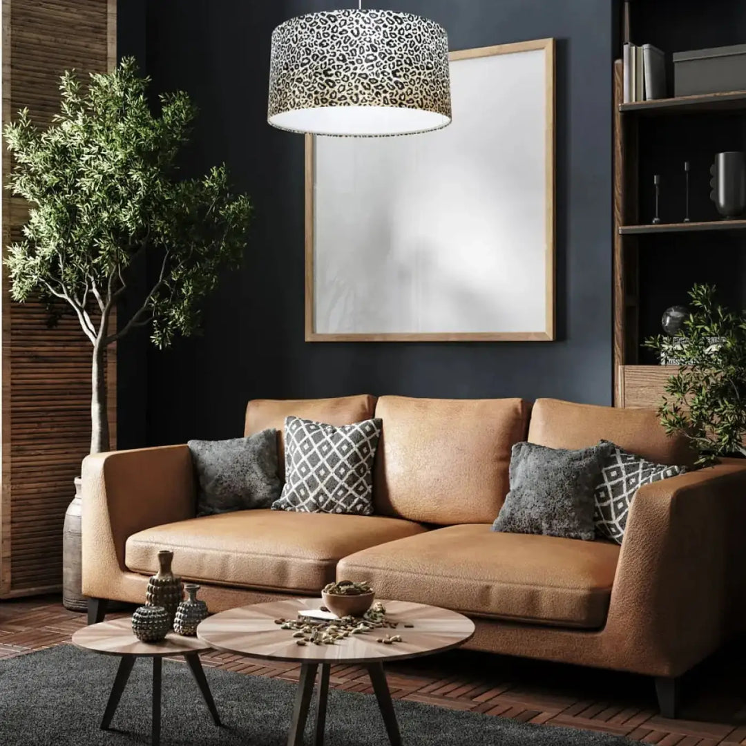 Suspension luminaire design léopard crème au-dessus d’un canapé en cuir tan avec coussins à motifs gris et blanc