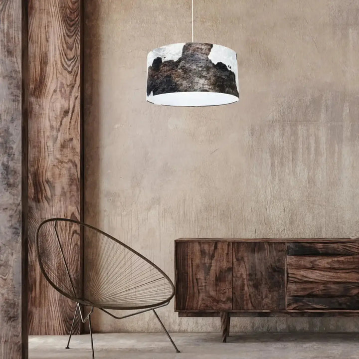 Suspension luminaire cylindrique marron blanc avec intérieur blanc et motif peau de vache noir et blanc suspendu par cordon fin