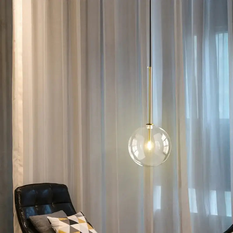 Suspension luminaire doré avec une boule en verre transparente

