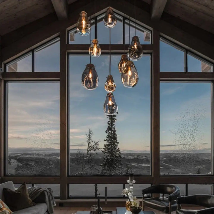 Un suspension luminaire vulco en verre avec ampoules filament exposées dans un agencement moderne aux tons chauds