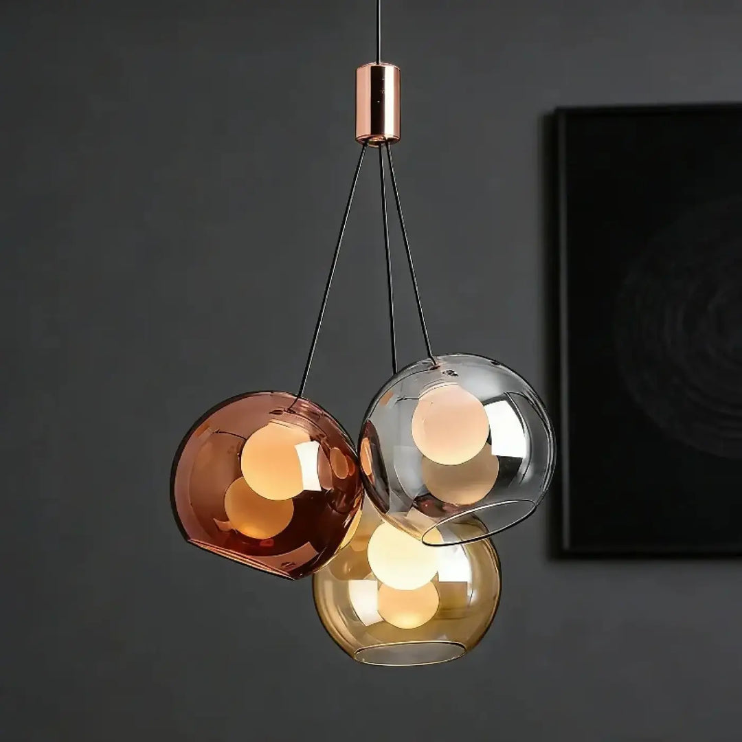 Suspension luminaire moderne trois ampoules troniu avec finitions cuivre et abat-jours sphériques en verre ambre et or pour salle à manger