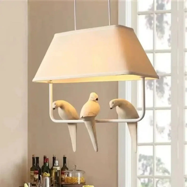 Suspension luminaire rectangulaire crème avec trois figurines d oiseaux blancs perchées sur son cadre lumibird