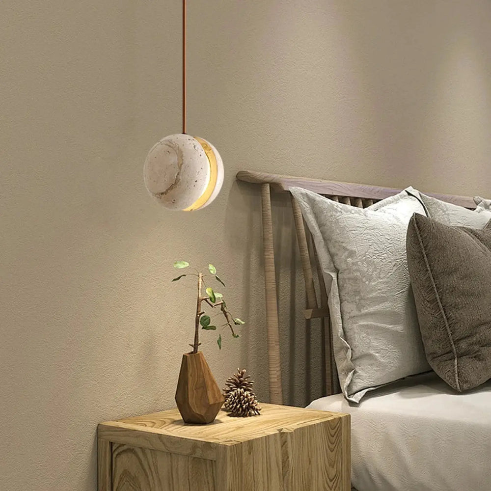 Suspension luminaire kreto sphérique minimaliste en béton texturé off-white avec halo doré chaleureux et travertin aux lignes élégantes