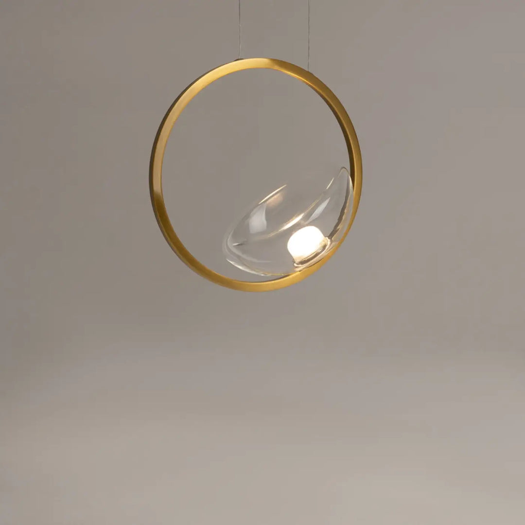 Suspension lunare led disque doré avec pendentif circulaire doré et globe en verre clair abritant une ampoule allumée
