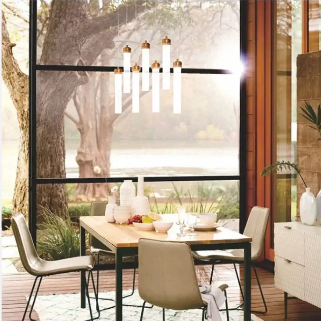 Suspension luminaire ilia avec tubes en verre rainuré blanc et embouts laiton au-dessus d’une table pour suspension minimaliste