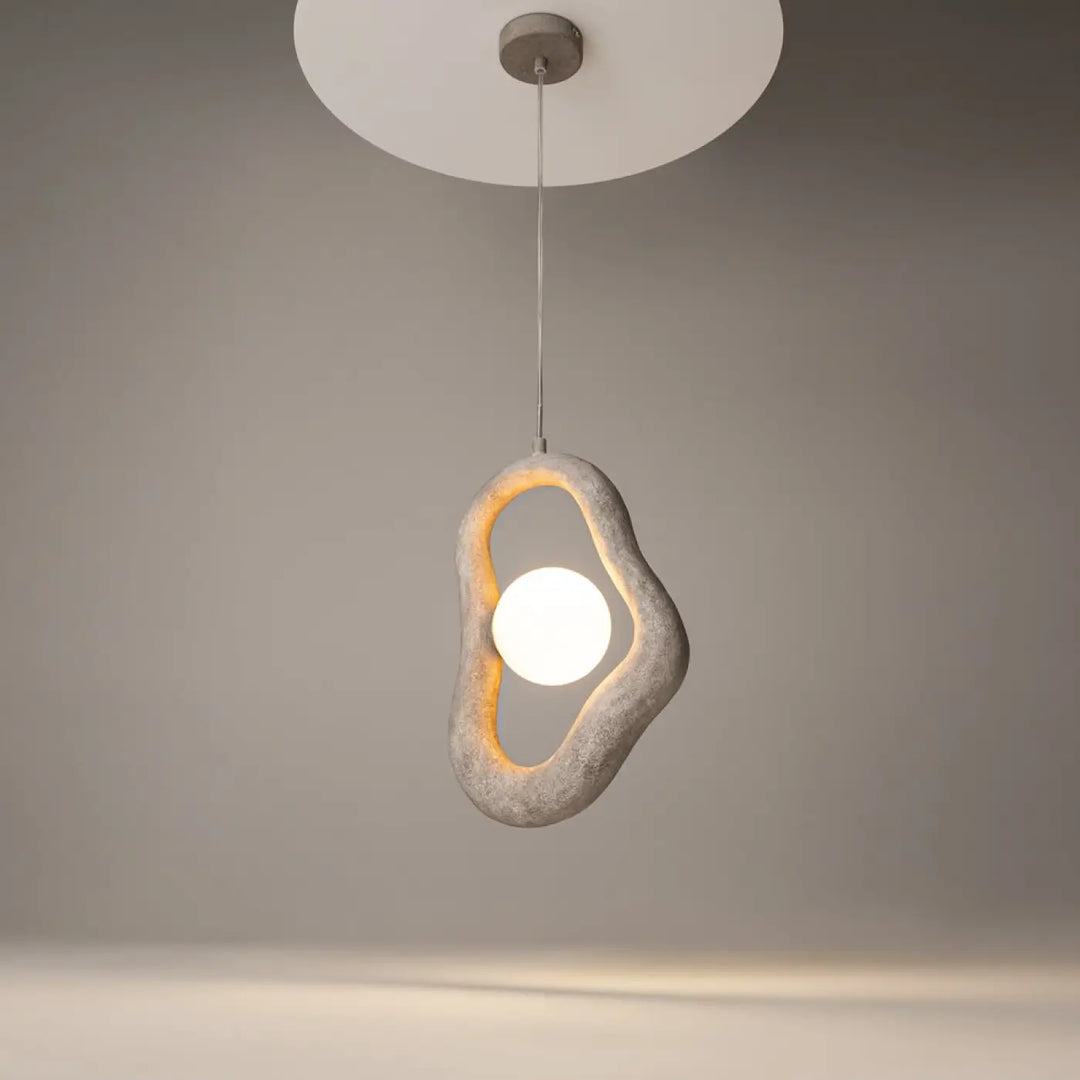 Suspension opus en béton gris texturé avec volume irrégulier entourant une lumière douce blanche