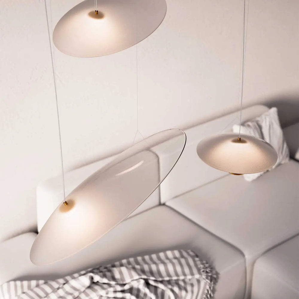 Trois suspensions luminaire oyster minimalistes avec disques de verre dépoli et fixations dorées au-dessus d un canapé blanc