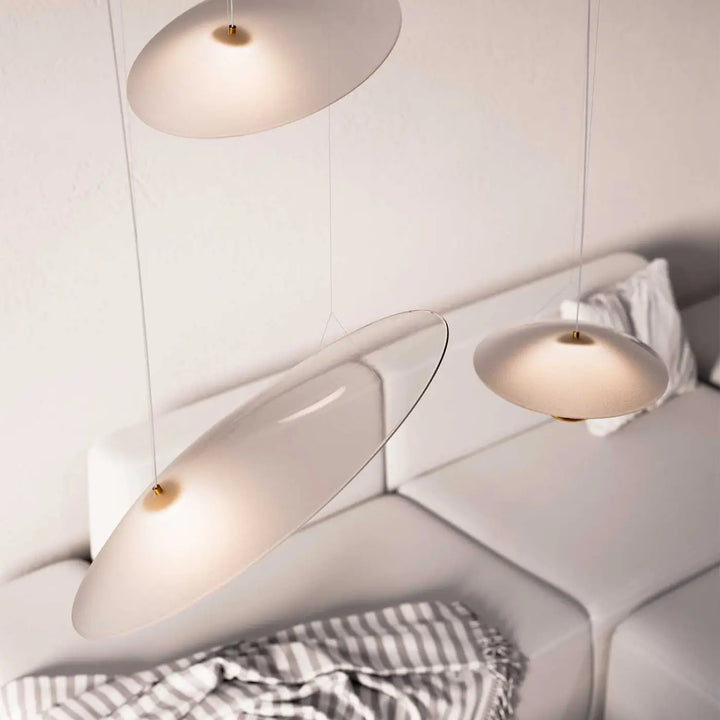 Trois suspensions luminaire oyster minimalistes avec disques de verre dépoli et fixations dorées au-dessus d un canapé blanc