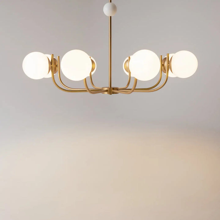 Suspension rendez vous avec branches dorées, cinq globes en verre transparent dépoli et un ornement central blanc sphérique