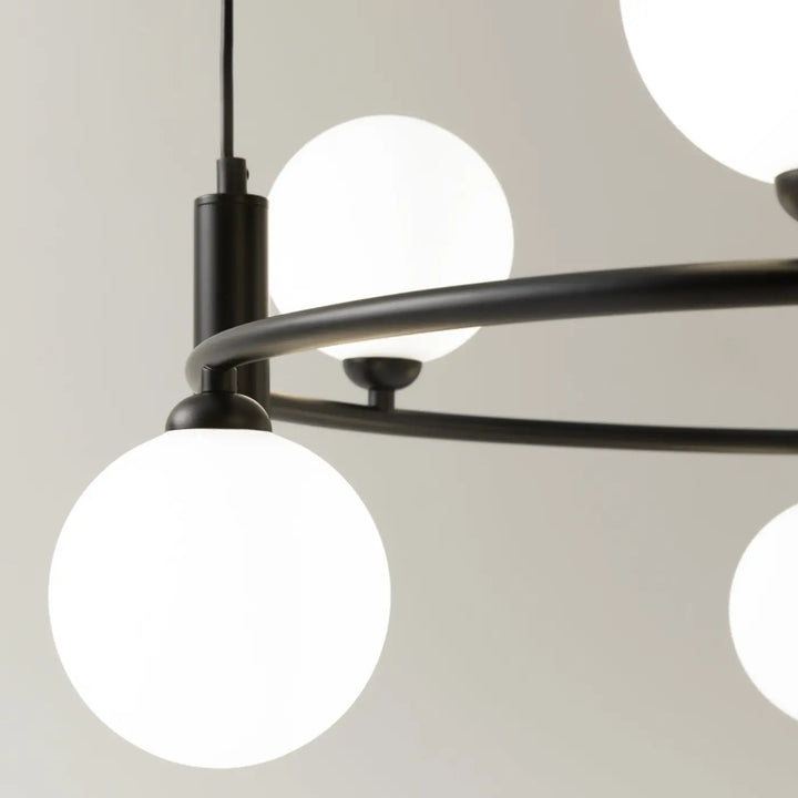 Suspension ring en métal noir avec globes en verre blanc givré offrant une touche art déco élégante