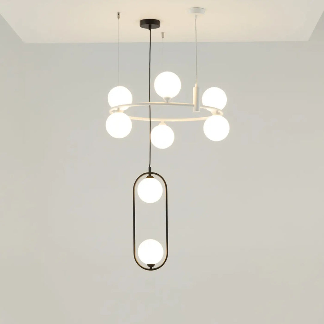 Suspension ring minimaliste au-dessus d’un îlot avec anneau circulaire et cadres ovales noirs tenant des globes en verre dépoli art déco