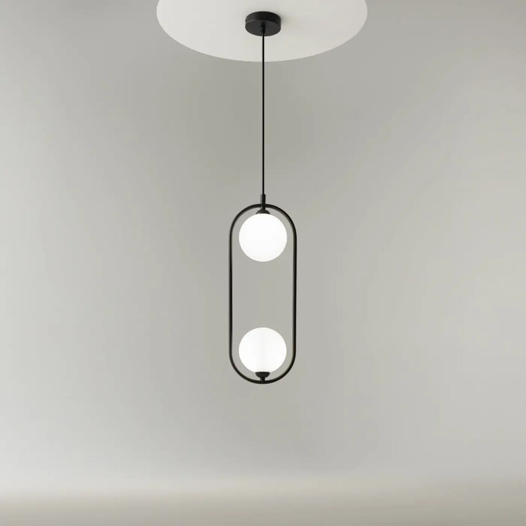 Suspension ring noire en métal moderne avec deux sphères en verre dépoli dans un cadre ovale art déco au-dessus d’un îlot