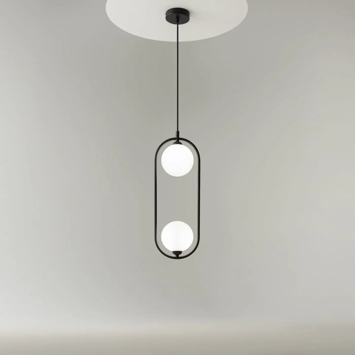 Suspension ring noire en métal moderne avec deux sphères en verre dépoli dans un cadre ovale art déco au-dessus d’un îlot