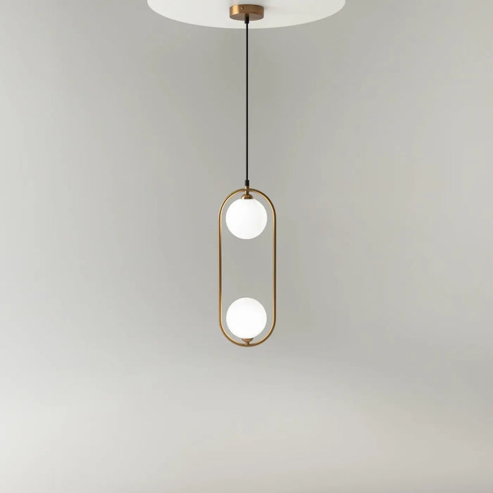 Suspension luminaire ring art déco avec deux globes en verre dépoli et structure en laiton au-dessus d’un îlot