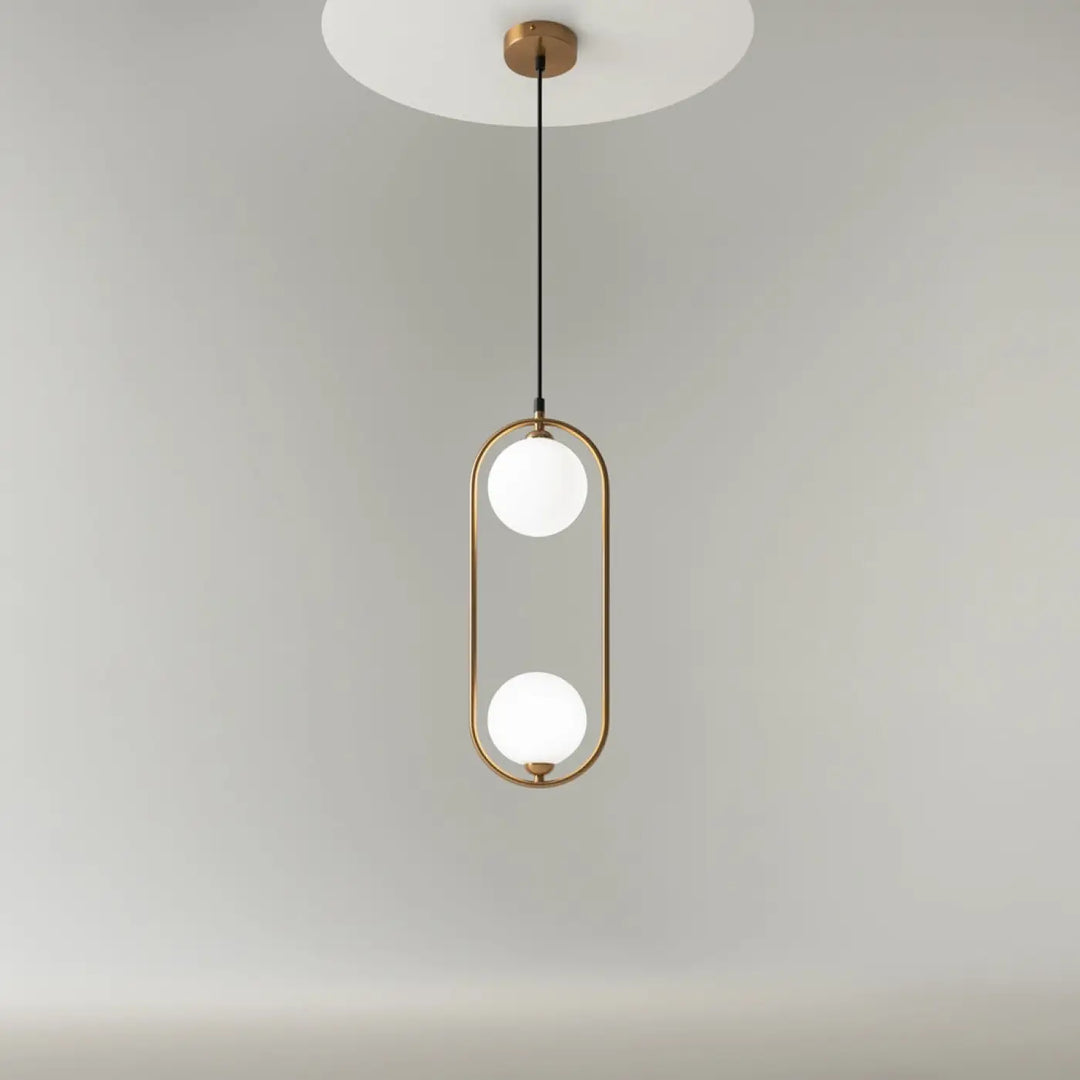Suspension ring art déco avec deux globes en verre dépoli dans un cadre ovale en laiton au-dessus d’un îlot minimaliste