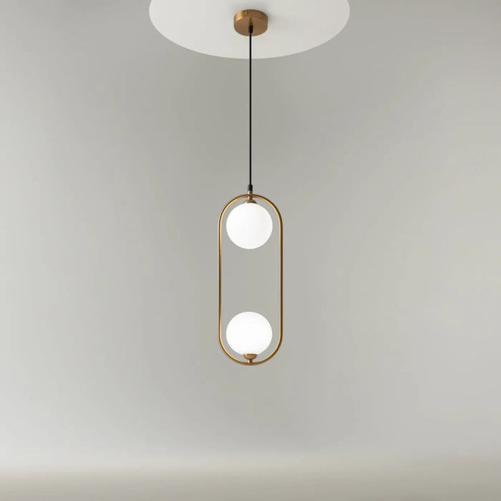 Suspension ring art déco avec deux globes en verre dépoli dans un cadre ovale en laiton au-dessus d’un îlot minimaliste