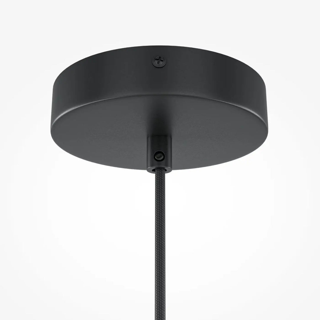 Suspension roots avec finition mate noire au-dessus d’une table en bois naturel avec base circulaire élégante et cordon texturé