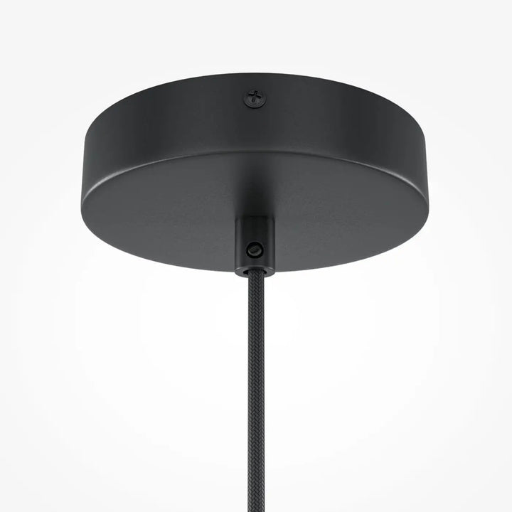 Suspension roots avec finition mate noire au-dessus d’une table en bois naturel avec base circulaire élégante et cordon texturé